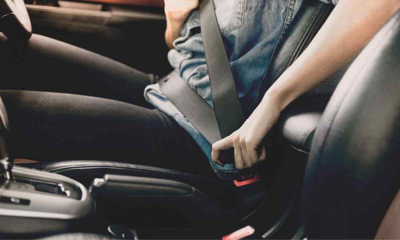 A person putting on a car seat belt